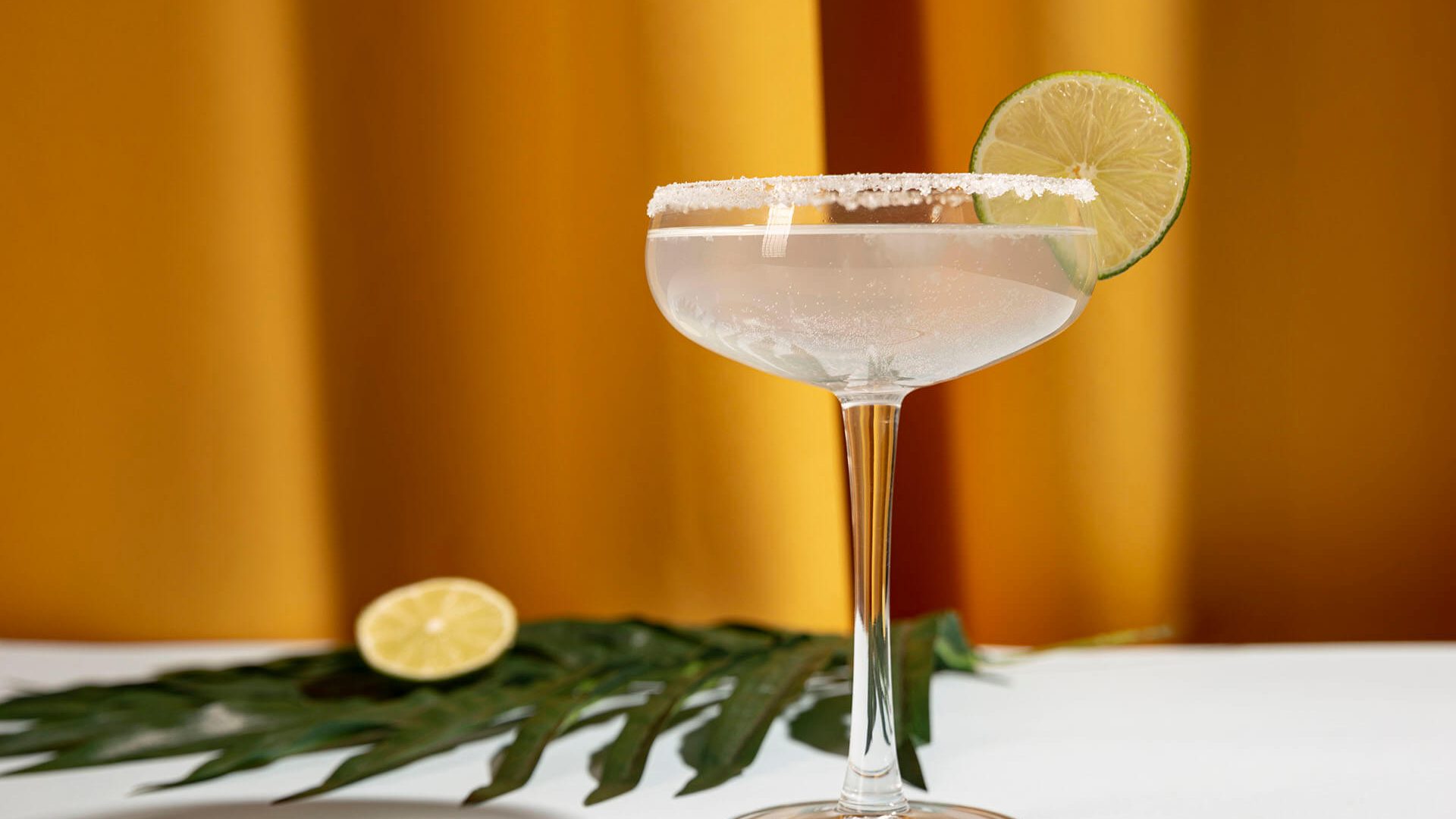 homemade-margarita-drink-with-lime-palm-leaf-table-against-yellow-curtain homemade-margarita-drink-with-lime-palm-leaf-table-against-yellow-curtain